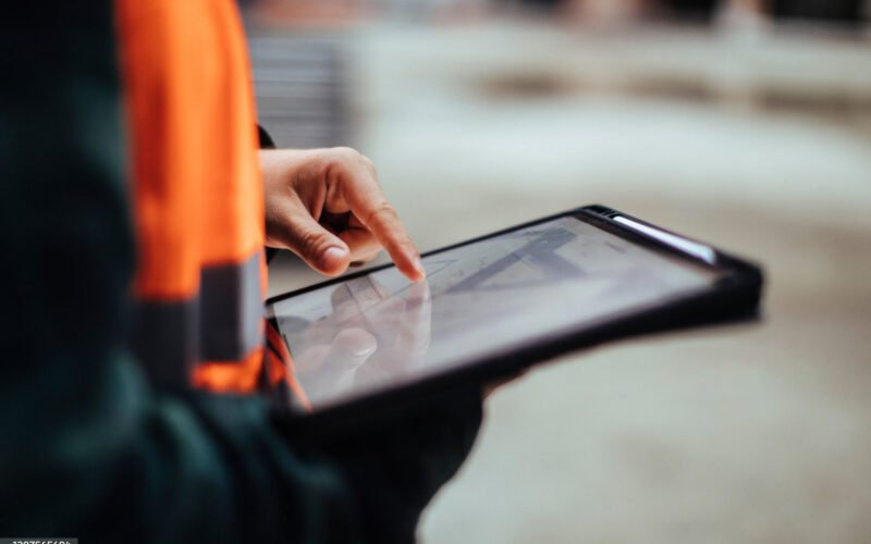 Engineer in a high-visibility jacket using a tablet