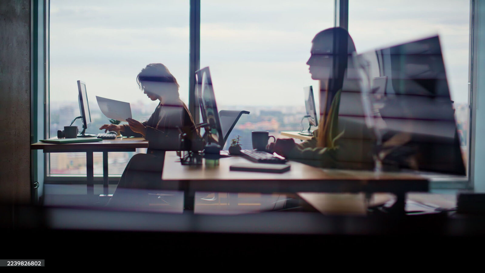 Person working at a desk by a large window in a high-rise office